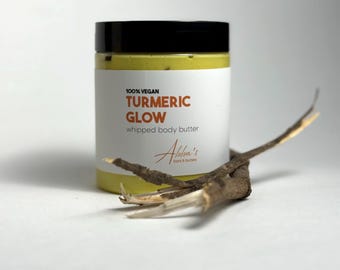 May include: A yellow jar of 100% vegan turmeric glow whipped body butter with a black lid and the text "100% Vegan Turmeric Glow whipped body butter" and "Abiba's Bars & Butters" on the label.