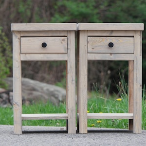 May include: Two wooden nightstands with a single drawer and a lower shelf. The nightstands are painted a light wood color and have black drawer pulls.