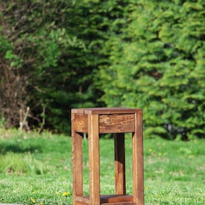 May include: A rustic wooden side table with a dark brown stain. The table has a simple design with a square top and four legs.