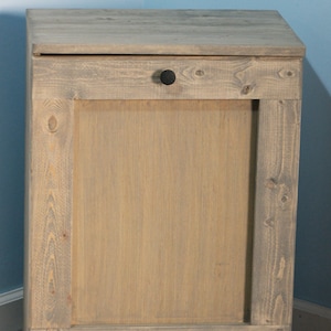 May include: A rustic oak trash can with a single door and black hardware. The can has a distressed wood finish and is made of solid wood.