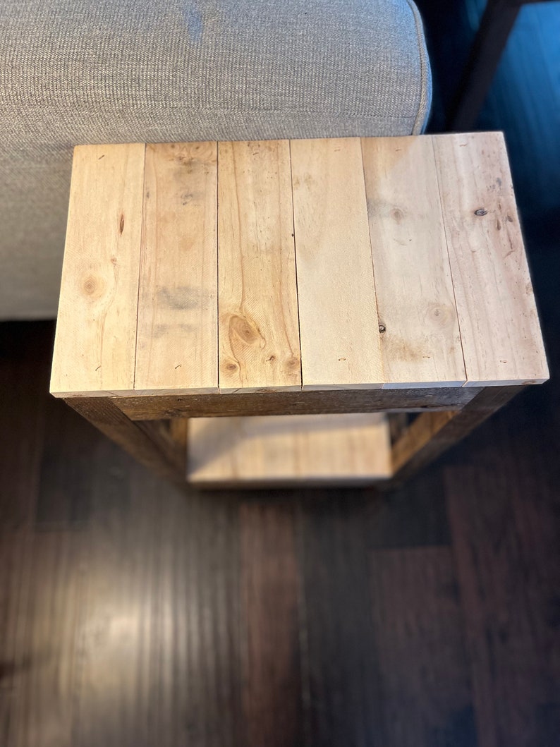 May include: A wooden side table with a natural wood finish. The table has a single shelf and is made of reclaimed wood.