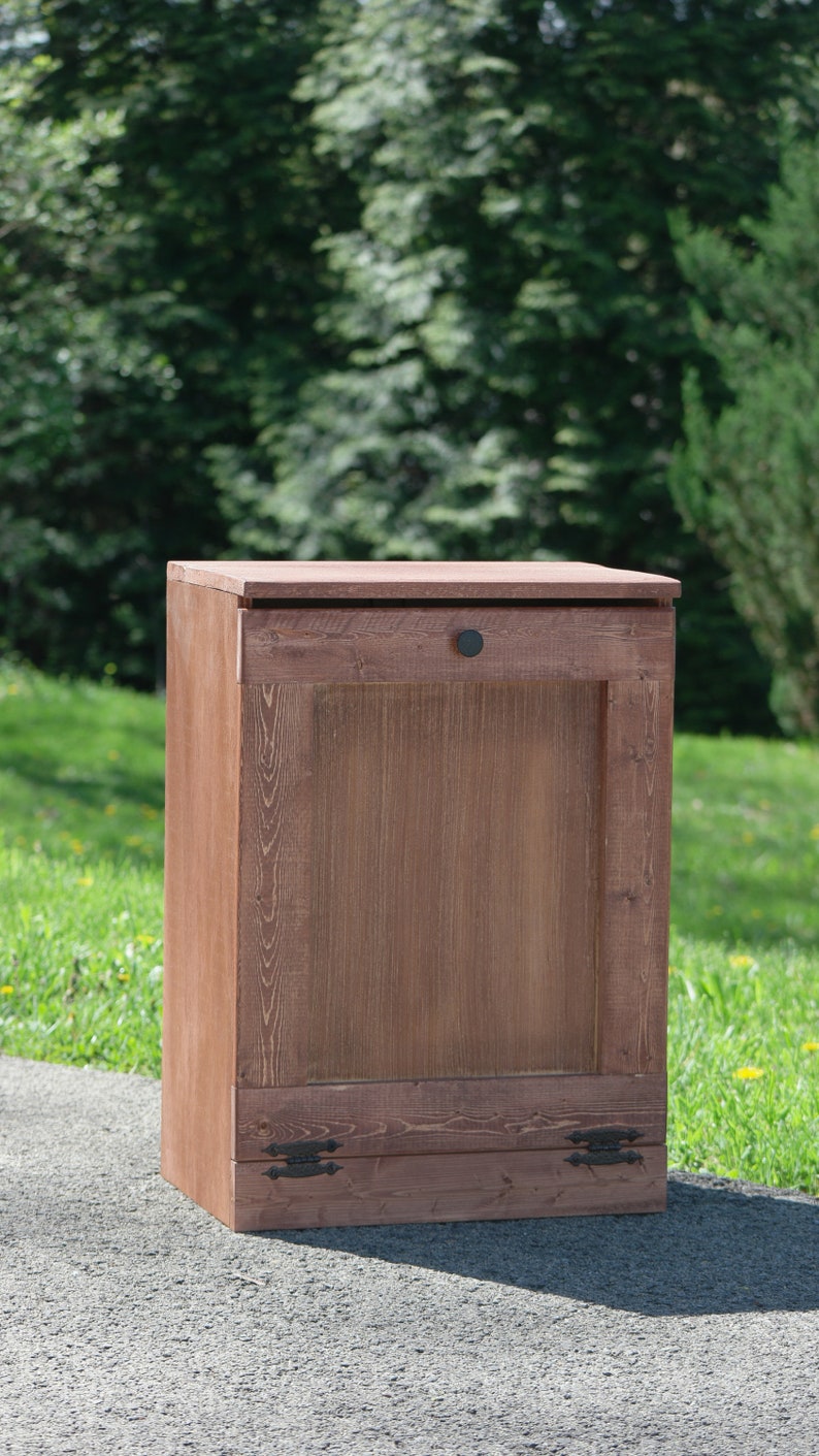 May include: A wooden storage cabinet with a single door and two drawers. The cabinet is stained a dark brown color and has black metal hardware.