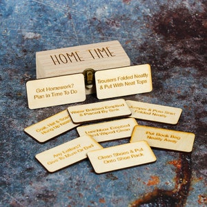 Wooden storage box with Home Time engraved on the lid and wooden tokens with engravings such as  put book bag away,water bottled emptied and placed by sink and other home time task examples on them.