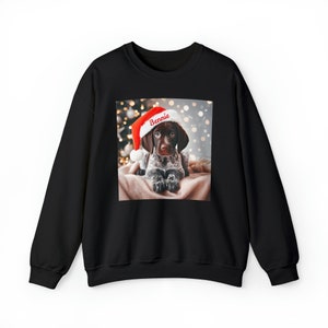 May include: Black sweatshirt with a printed image of a dog wearing a Santa hat. The dog's name, "Bennie", is written on the hat.
