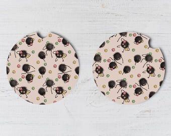 May include: Two round, pink and white coasters with a black and white pattern of cartoon creatures with pink and green stars.