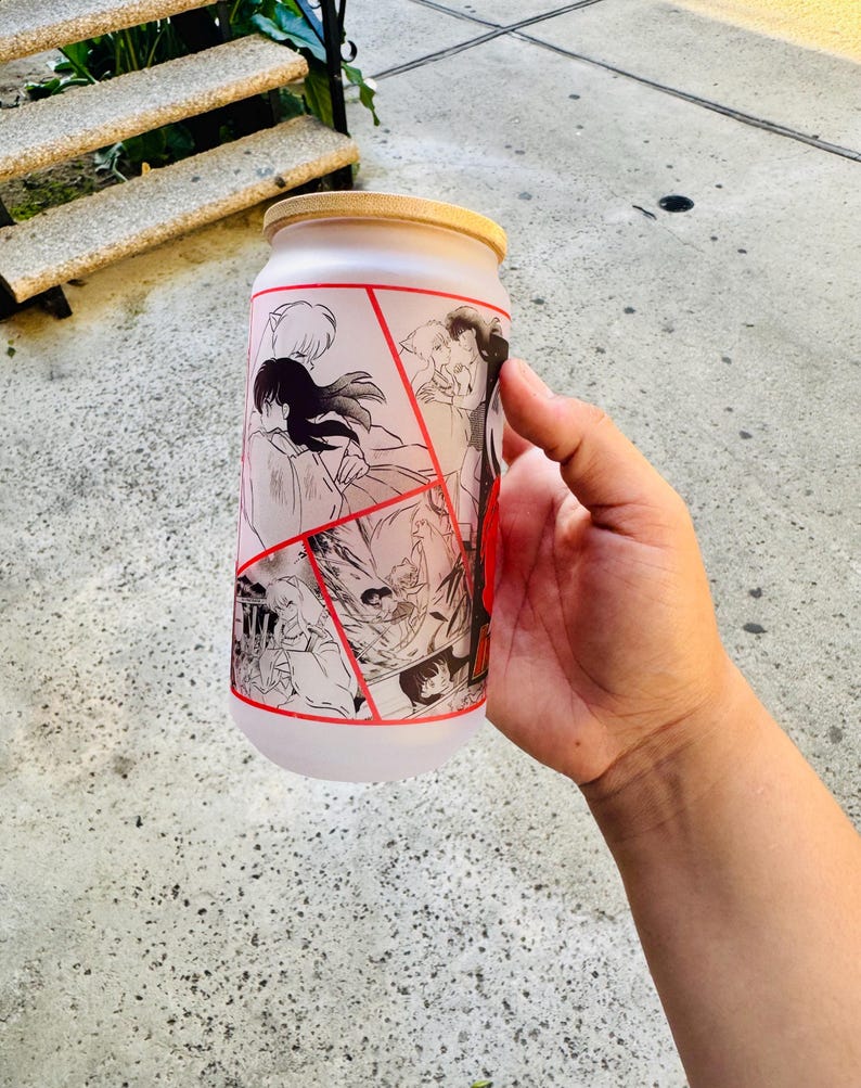 May include: A frosted glass water bottle with a black and white anime graphic print. The graphic features multiple characters from the anime series Inuyasha. The bottle has a red and white lid.
