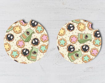 May include: Two round coasters with a white background and a pattern of black and white cookies, green and pink star-shaped cookies, and a green and white box with a black eye.