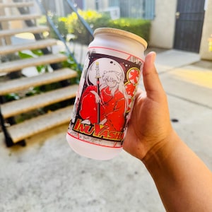 May include: White reusable water bottle with a black and white anime illustration of a character with red hair and a red outfit. The character is holding a sword and the text "Inuyasha" is visible on the bottle.