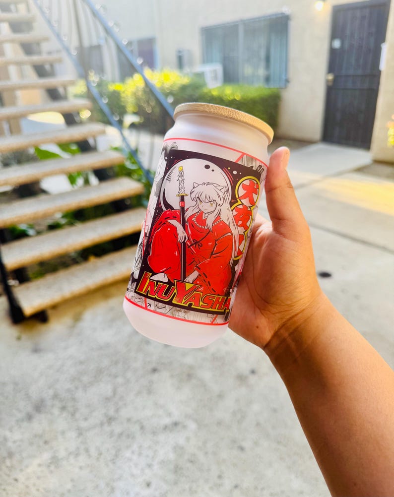 May include: White reusable water bottle with a black and white anime illustration of a character with red hair and a red outfit. The character is holding a sword and the text "Inuyasha" is visible on the bottle.