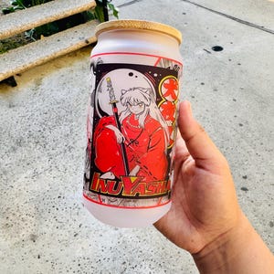 May include: A white frosted glass tumbler with a bamboo lid featuring a colorful anime illustration of a character with red hair and a sword. The text "Inuyasha" is printed on the bottom of the tumbler.