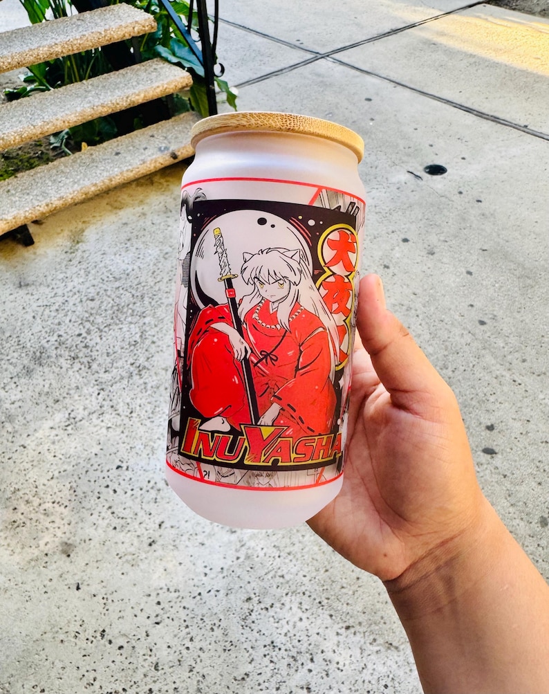 May include: A white frosted glass tumbler with a bamboo lid featuring a colorful anime illustration of a character with red hair and a sword. The text "Inuyasha" is printed on the bottom of the tumbler.