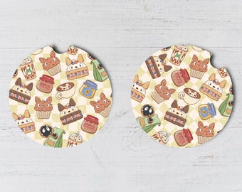 May include: Two round beverage coasters with a white background and a repeating pattern of cartoon cupcakes, coffee cups, and jars of jam. The pattern is in shades of brown, pink, blue, and green.
