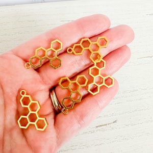May include: Five gold metal honeycomb charms with a loop for attaching to jewelry or other crafts.