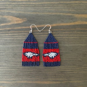 May include: A pair of long, beaded earrings with a red, white, and blue color scheme. The earrings are made of small, round beads and have a fringe-like design.