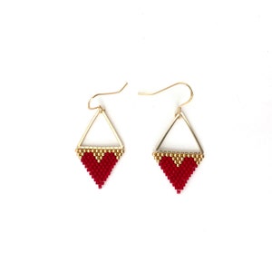 May include: A pair of gold triangle earrings with red heart-shaped beading.