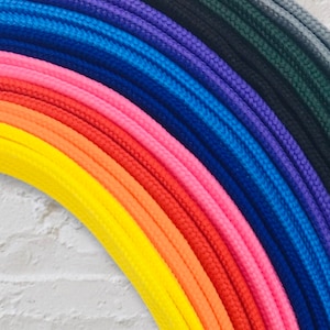 May include: A rainbow assortment of colourful cords, arranged in a semi-circle, with the colours ranging from dark blue to yellow.