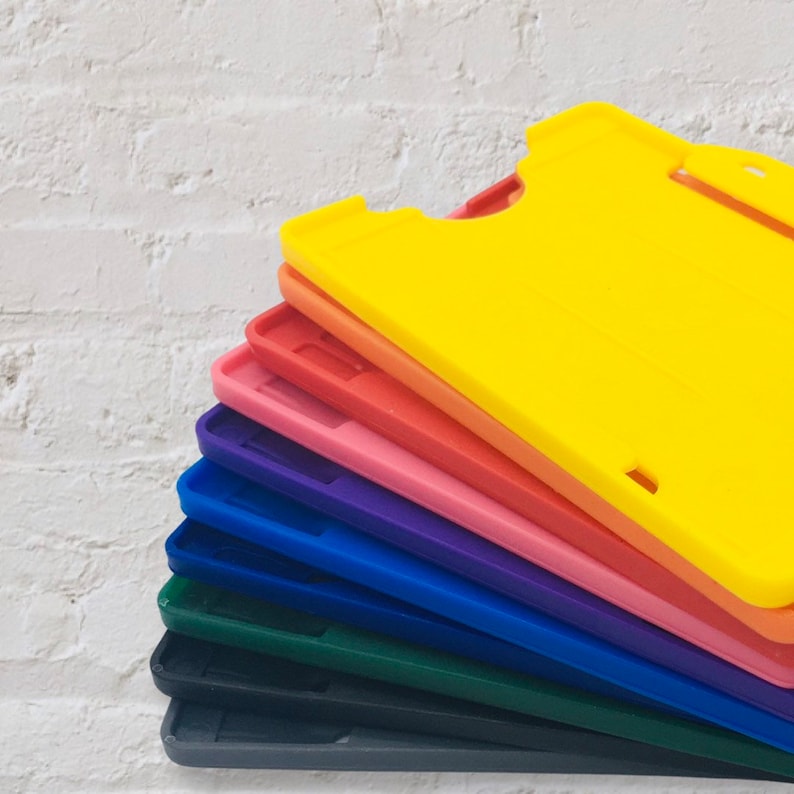 May include: A stack of ten colourful plastic ID card holders. The holders are arranged in a rainbow pattern, starting with yellow at the top and ending with grey at the bottom.