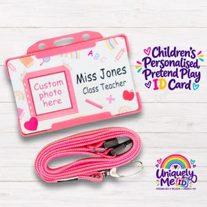 May include: A pink plastic ID card holder with a matching pink lanyard. The card features a white background with colourful school-themed icons, a pink frame for a photo, and the printed text: Custom photo here, Miss Jones, Class Teacher.