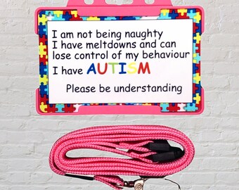 Puede incluir: Lanyard rosa con un porta-tarjetas de identificación de plástico con un borde de piezas de rompecabezas de colores. La tarjeta tiene el texto "No estoy siendo travieso Tengo colapsos y pierdo el control de mi comportamiento Tengo AUTISMO Por favor, sea comprensivo".