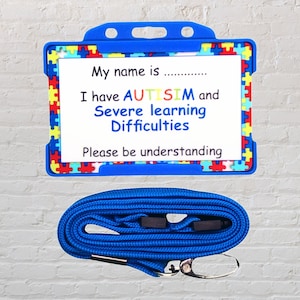 Op de afbeelding: Blauwe lanyard met een blauwe plastic ID-kaarthouder. De kaarthouder heeft een witte achtergrond met de tekst "My name is...... I have AUTISIM and Severe learning Difficulties Please be understanding" in zwart gedrukt. De kaarthouder is versierd met een kleurrijk puzzelstukjespatroon.