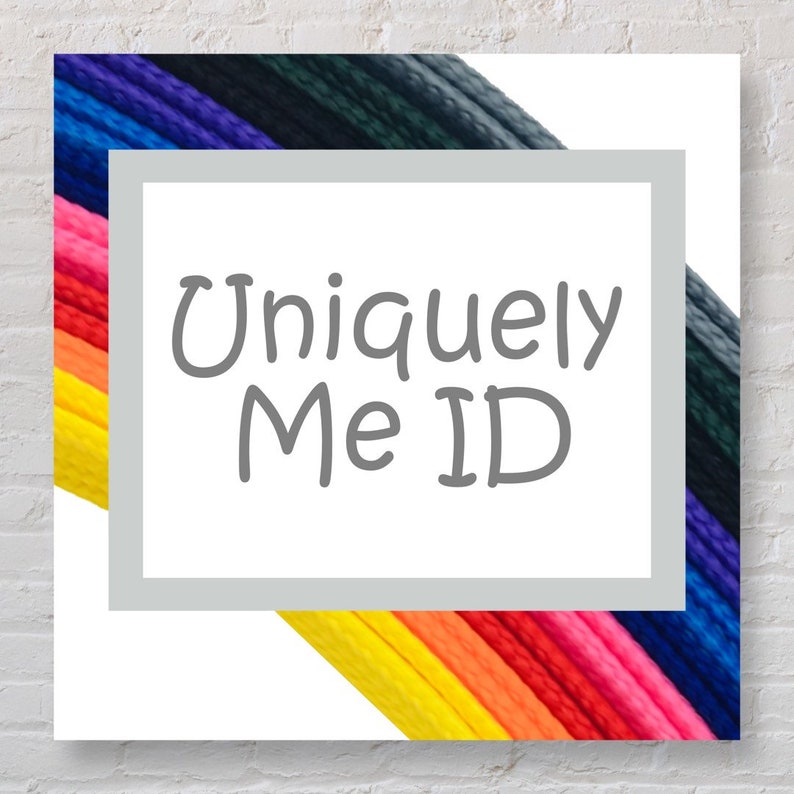 May include: A white square with a grey border and the text "Uniquely Me ID" in grey. The square is partially covered by a rainbow of colourful cords.