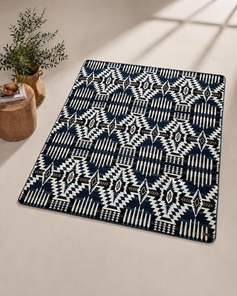 May include: A rectangular rug with a geometric pattern in navy blue, white, and brown. The design features diamond and zigzag shapes. The rug is placed on a light-colored surface.