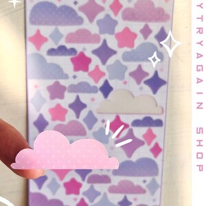 May include: A sheet of pastel purple, pink, and white aesthetic sky stickers featuring clouds and stars. The sticker sheet says "Aesthetic Sky Deco Sticker Sheet" at the top.