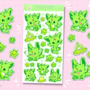 May include: A sticker sheet featuring various green alien creature designs with red accents, along with UFO and star stickers. The sheet has the text "GIANT SHINY ELTON STICKER SHEET" and "trytryagain shop". The stickers are on a pink background.
