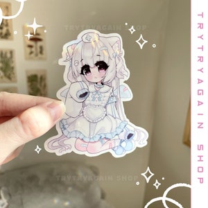 K&ouml;nnte beinhalten: Ein wei&szlig;er und blauer Anime-Aufkleber mit einem M&auml;dchen mit wei&szlig;en Haaren, das ein wei&szlig;es Kleid mit einem blauen Kragen und einer blauen Schleife tr&auml;gt. Sie hat ein wei&szlig;es Stirnband mit einem roten Kreuz darauf. Der Aufkleber hat eine holografische Oberfl&auml;che.