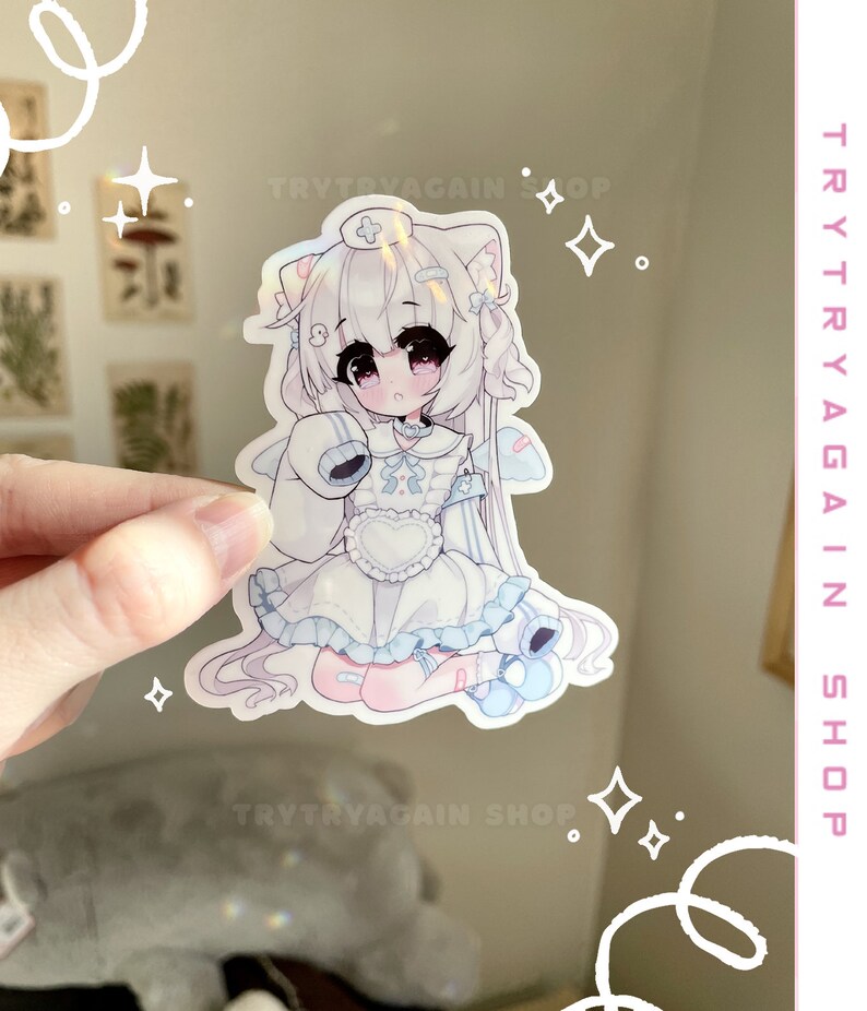 K&ouml;nnte beinhalten: Ein wei&szlig;er und blauer Anime-Aufkleber mit einem M&auml;dchen mit wei&szlig;en Haaren, das ein wei&szlig;es Kleid mit einem blauen Kragen und einer blauen Schleife tr&auml;gt. Sie hat ein wei&szlig;es Stirnband mit einem roten Kreuz darauf. Der Aufkleber hat eine holografische Oberfl&auml;che.