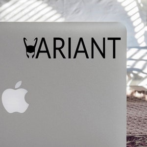 May include: A silver laptop with a black sticker that says "VARIANT" and a black silhouette of a horned helmet. The laptop has a white Apple logo.