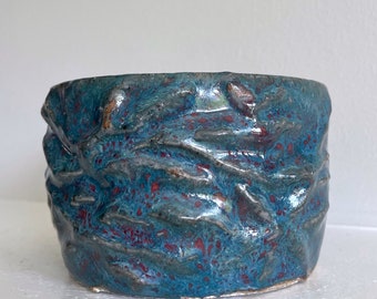 Petit vase de poterie en céramique fait main bleu et rouge avec texture de racines