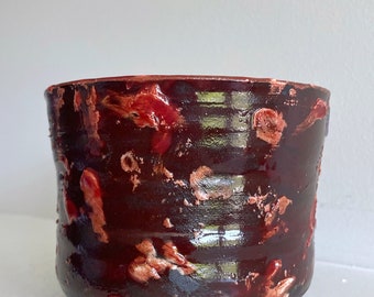 Petit vase de poterie en céramique fait main rouge noir et blanc avec des taches de texture taches sur l'argile noire