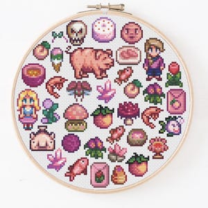 May include: A circular wooden embroidery hoop containing a cross-stitch pattern featuring a collection of pixel art icons. The design includes a pig, two human figures, various fruits, flowers, crystals, fish, shrimp, mushrooms, and a skull.