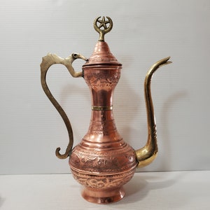 Peut inclure: Une cafetière turque en cuivre et en laiton avec un motif orné et un fleuron en forme d'étoile et de croissant de lune.