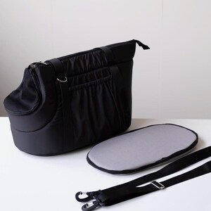 Puede incluir: Bolsa de transporte para mascotas negra con una ventana de malla, un coj&iacute;n gris extra&iacute;ble y una correa de hombro ajustable.