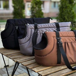 Puede incluir: Tres bolsas de transporte para mascotas en negro, gris y marr&oacute;n. Las bolsas tienen un interior acolchado y un cierre de cremallera. Tienen correas ajustables y un asa.