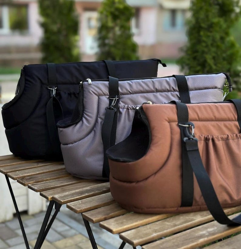 Puede incluir: Tres bolsas de transporte para mascotas en negro, gris y marr&oacute;n. Las bolsas tienen un interior acolchado y un cierre de cremallera. Tienen correas ajustables y un asa.