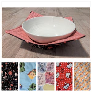 May include: A white ceramic bowl rests on a reversible bowl cozy. The cozy features a pink and black floral pattern on one side and a pink textured pattern on the other. Additional fabric swatches show various patterns.