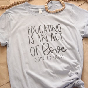Educar es un acto de amor Camisa católica / Camiseta católica / Camisa de cita del Papa Francisco / Regalo de camisa de maestro católico / Escuela católica en el hogar