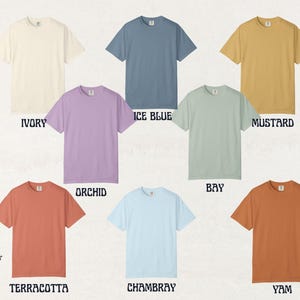May include: A collection of eight short-sleeved t-shirts in various colors, including ivory, ice blue, mustard, orchid, bay, terracotta, chambray, and yam. Each shirt is displayed on a neutral background with the color name below.