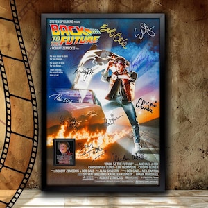 May include: A movie poster for the film "Back to the Future" featuring a DeLorean time machine and the main character, Marty McFly, standing in front of it. The poster is signed by the cast and crew, including Michael J. Fox, Christopher Lloyd, Lea Thompson, and Steven Spielberg.