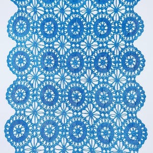 May include: A close-up of a blue crocheted lace runner. The runner features a repeating pattern of circular and floral designs. The edges are scalloped. The lace is a vibrant shade of blue.