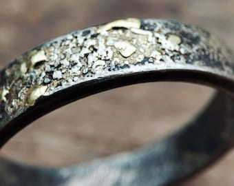 Puede incluir: Una banda de plata con una superficie texturizada y pequeños detalles dorados.