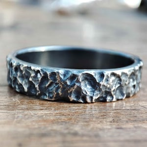 May include: A silver band ring with a textured, hammered finish.