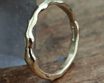 May include: A gold ring with a textured, irregular, and slightly wavy band.
