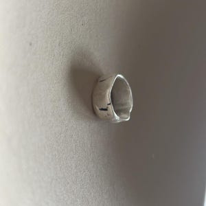 May include: A silver ring with a textured, irregular shape.