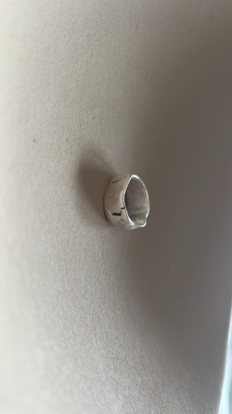 May include: A silver ring with a textured, irregular shape.