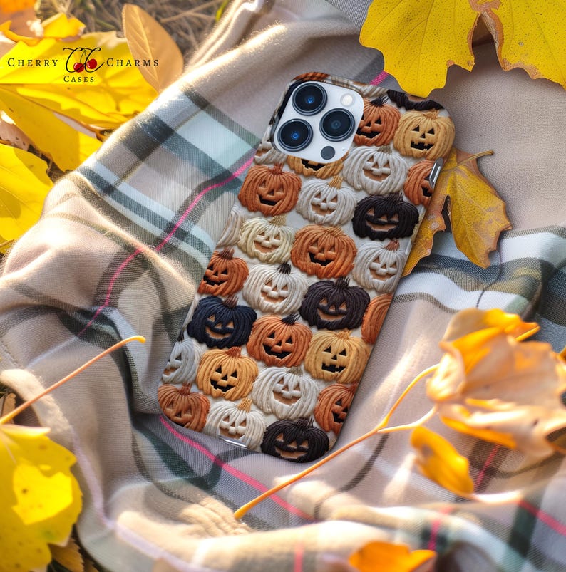 Puede incluir: Una funda para tel&eacute;fono con tem&aacute;tica de Halloween con un patr&oacute;n de caras de calabaza naranja, blanca y negra. La funda est&aacute; hecha para un iPhone con una protuberancia de c&aacute;mara.