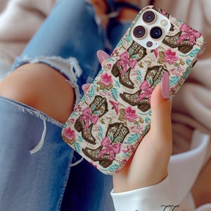 May include: A white phone case featuring a pattern of pink bows and brown cowboy boots. The case has a camera lens cutout and a floral design.